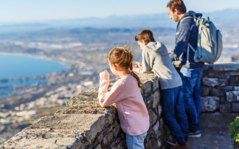 A family enjoys the breathtaking view from a scenic lookout in Cape Town, South Africa. With well-maintained trails and family-friendly attractions, it’s a great destination for safe adventures.